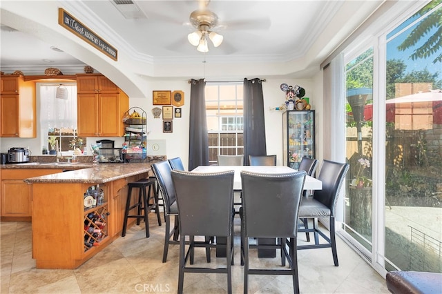 tiled dining area with a tray ceiling, ceiling fan, and ornamental molding