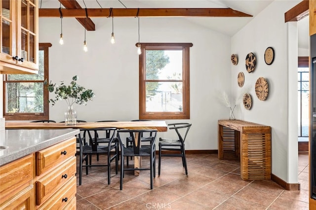 tiled dining space featuring vaulted ceiling with beams