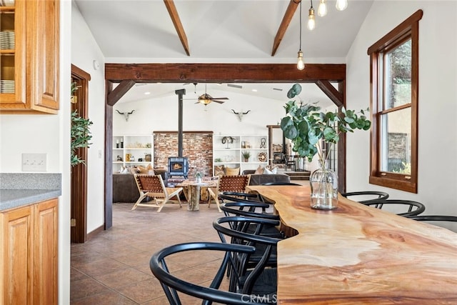 tiled dining room with vaulted ceiling with beams, a wood stove, and ceiling fan