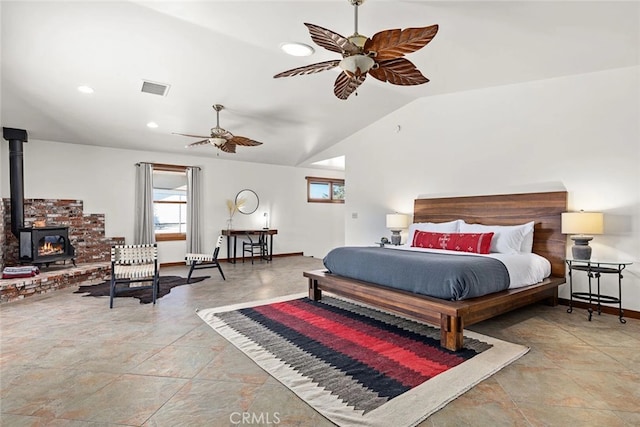 bedroom featuring ceiling fan, a wood stove, and vaulted ceiling