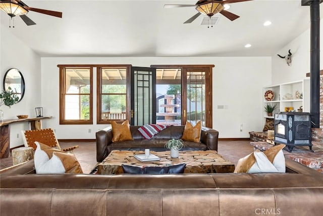 living room with carpet, a wood stove, and ceiling fan