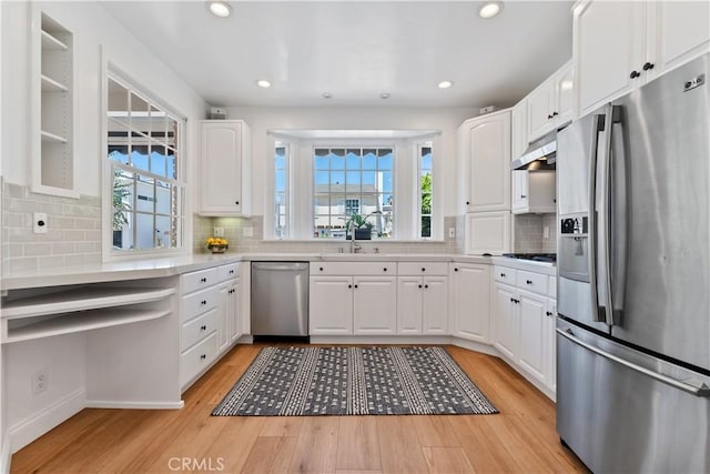 kitchen with sink, stainless steel appliances, backsplash, light hardwood / wood-style floors, and white cabinets