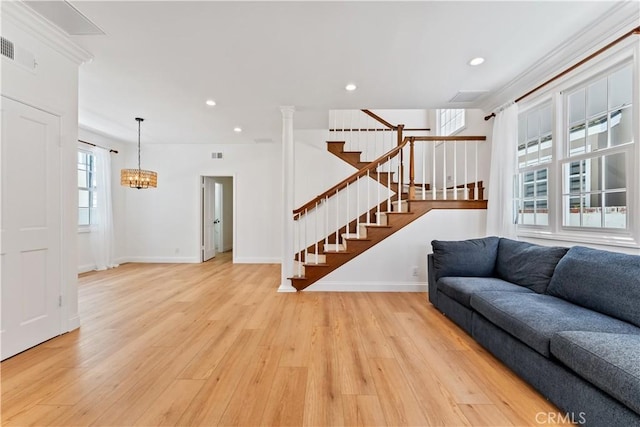 living room with light hardwood / wood-style floors, an inviting chandelier, and ornamental molding