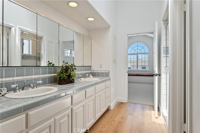 bathroom featuring wood-type flooring, vanity, a wealth of natural light, and backsplash