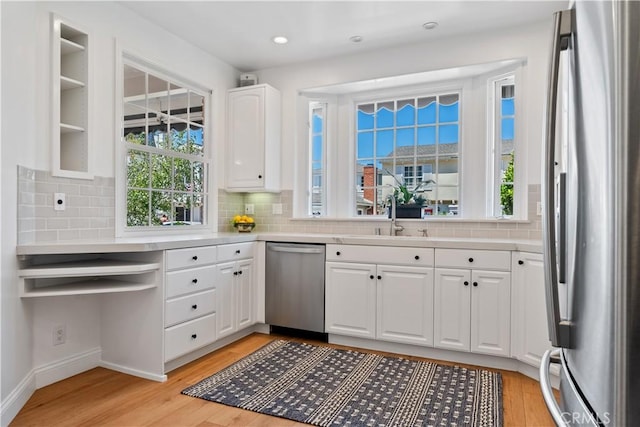 kitchen featuring white cabinetry, sink, stainless steel appliances, tasteful backsplash, and light hardwood / wood-style floors