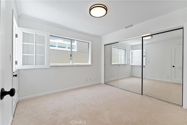 unfurnished bedroom featuring light colored carpet, ornamental molding, and a closet