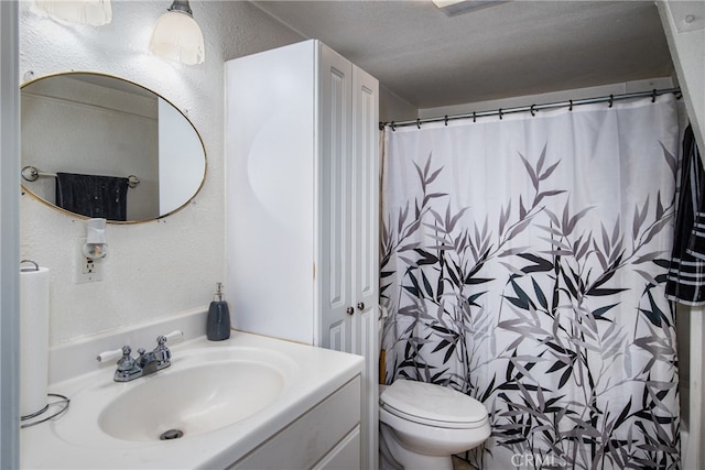 bathroom featuring a textured ceiling, walk in shower, vanity, and toilet