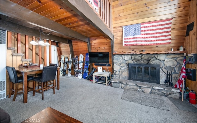 carpeted living room with a fireplace, wood walls, beam ceiling, and wood ceiling