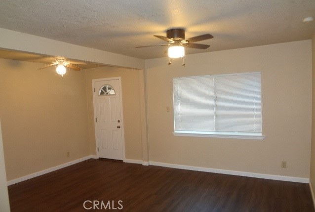 unfurnished room with ceiling fan, a textured ceiling, and dark hardwood / wood-style floors