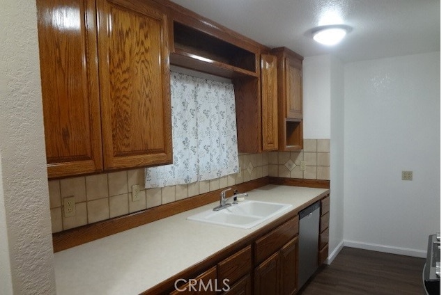 kitchen with dishwasher, dark wood-type flooring, sink, and decorative backsplash