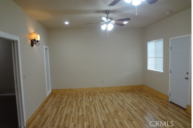 spare room with light wood-type flooring and ceiling fan