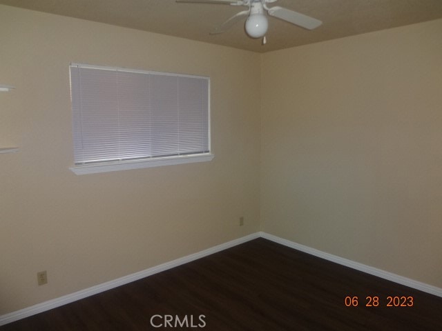 empty room with dark hardwood / wood-style flooring and ceiling fan