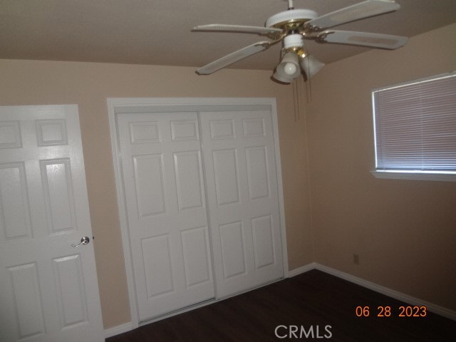 unfurnished bedroom with a closet, ceiling fan, and dark wood-type flooring