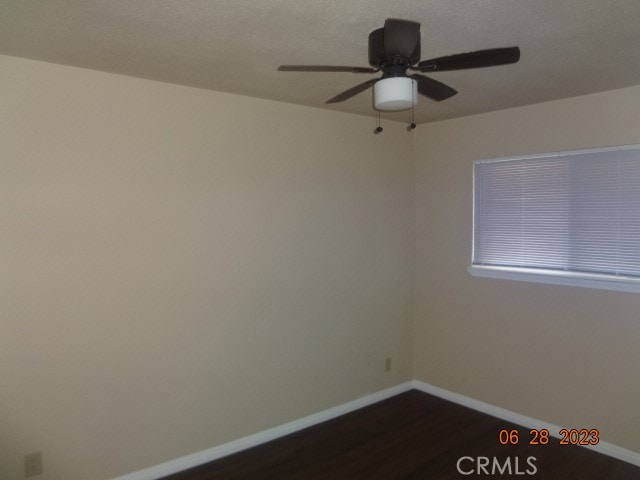 empty room with ceiling fan and dark hardwood / wood-style floors