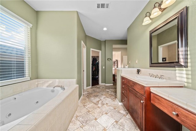 bathroom featuring tiled tub and vanity