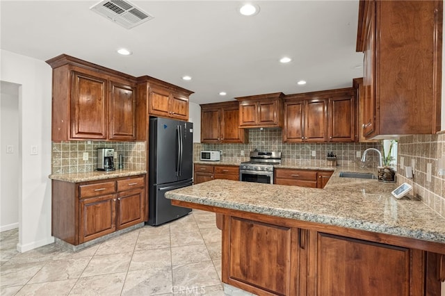 kitchen with backsplash, kitchen peninsula, appliances with stainless steel finishes, and sink