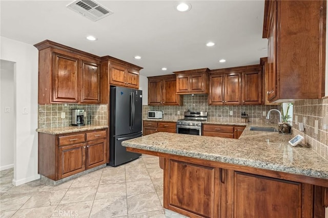 11319 Choctaw Dr, Bakersfield, CA 93308 - kitchen featuring freestanding refrigerator, stainless steel range, decorative backsplash, a peninsula, and light stone counters