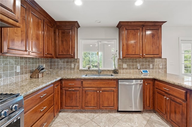 kitchen with appliances with stainless steel finishes, light stone countertops, sink, and tasteful backsplash