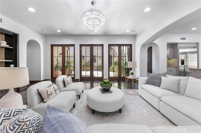 living room with french doors, light wood-type flooring, and a notable chandelier