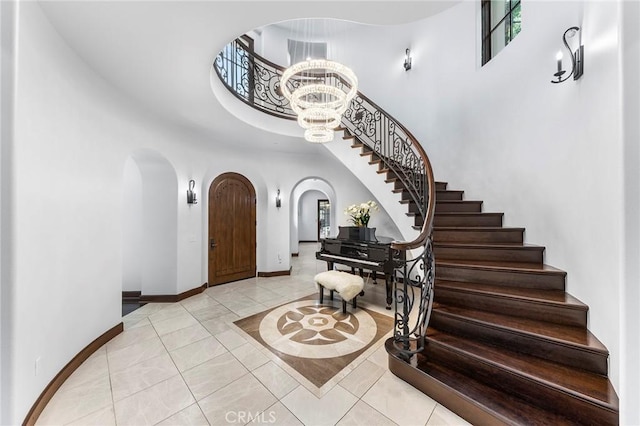 foyer entrance featuring a high ceiling, light tile patterned floors, and an inviting chandelier