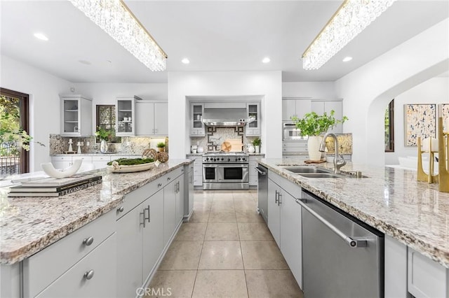 kitchen with backsplash, sink, appliances with stainless steel finishes, and an island with sink