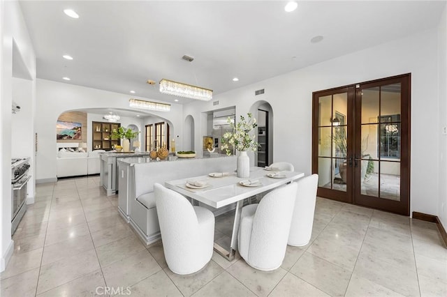 dining area featuring french doors, light tile patterned floors, and an inviting chandelier