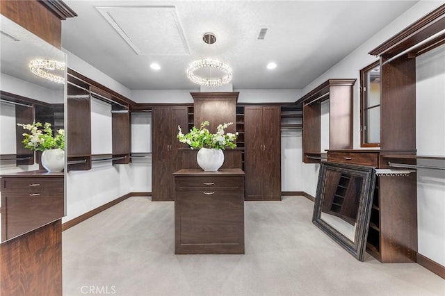 walk in closet with light colored carpet and a notable chandelier