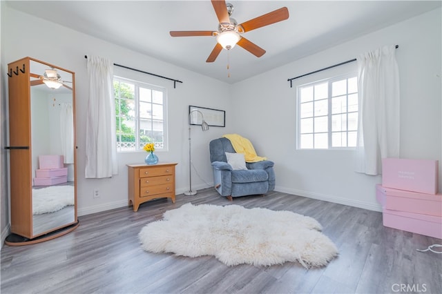 living area with wood-type flooring and ceiling fan