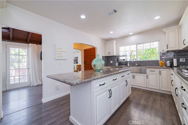 kitchen featuring a center island, white cabinets, a healthy amount of sunlight, and sink