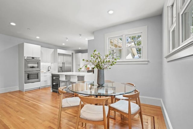 dining area with wine cooler, sink, and light hardwood / wood-style flooring