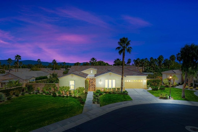 mediterranean / spanish home featuring a yard and a garage