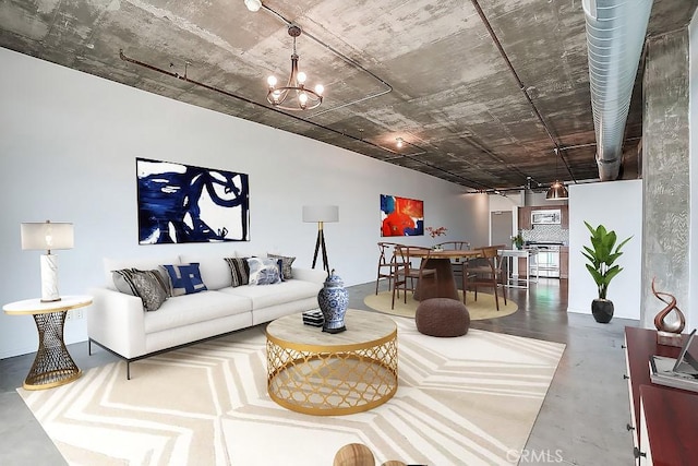 living room featuring a chandelier and concrete floors