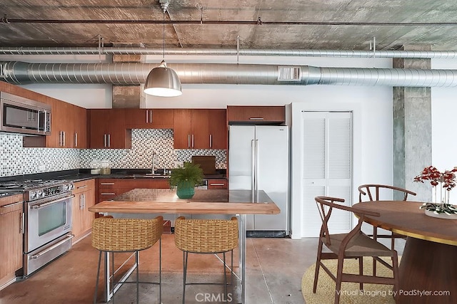 kitchen featuring decorative backsplash, high quality appliances, sink, and pendant lighting