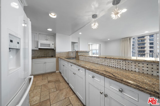 kitchen featuring white cabinets, sink, hanging light fixtures, tasteful backsplash, and a chandelier