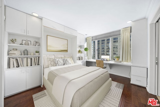 bedroom with built in desk and dark wood-type flooring