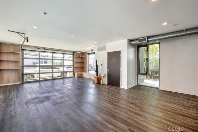 unfurnished living room with built in shelves and dark wood-type flooring