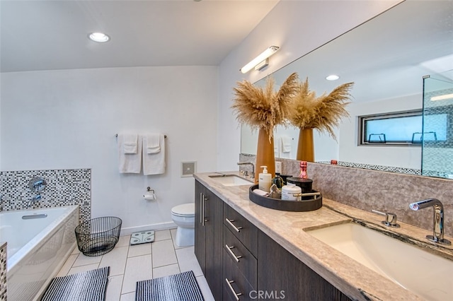 bathroom with tile patterned flooring, vanity, tiled bath, and toilet