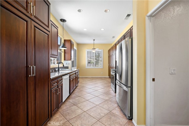 kitchen with sink, stainless steel appliances, light tile patterned floors, decorative light fixtures, and light stone countertops