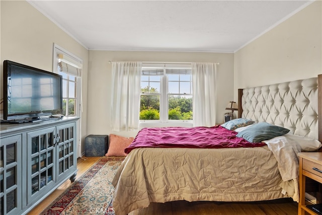 bedroom featuring wood-type flooring, ornamental molding, and multiple windows