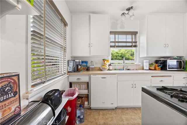 kitchen with dishwasher, stove, white cabinetry, and sink