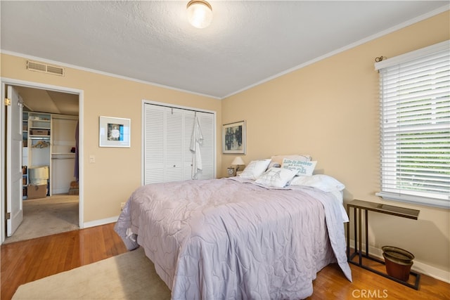 bedroom with ornamental molding, a closet, hardwood / wood-style flooring, and a textured ceiling