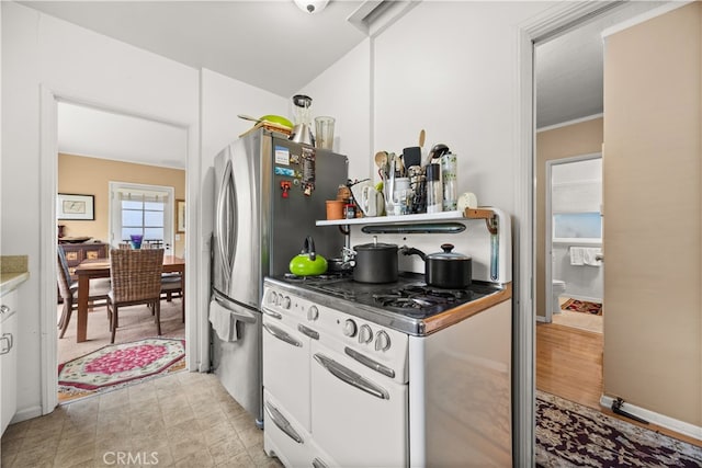 kitchen featuring stainless steel refrigerator, white range with gas stovetop, and light hardwood / wood-style flooring