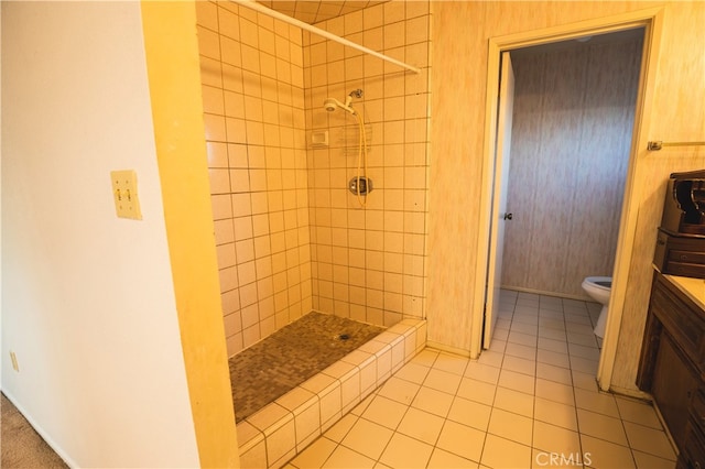 bathroom featuring vanity, a tile shower, toilet, and tile patterned flooring