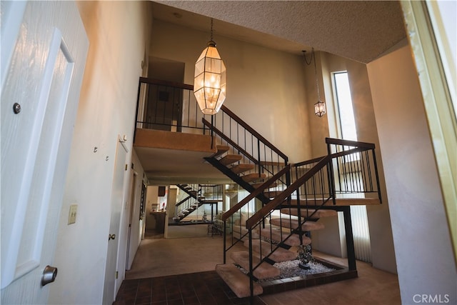 stairs featuring a textured ceiling, carpet floors, and a towering ceiling