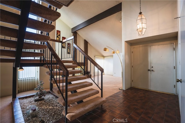 entryway featuring high vaulted ceiling and dark tile patterned floors