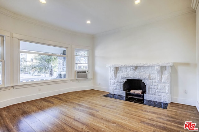 unfurnished living room with cooling unit, crown molding, hardwood / wood-style floors, and a stone fireplace