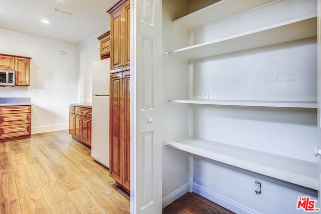 interior space with light hardwood / wood-style floors and white fridge