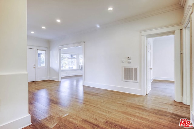 spare room with light wood-type flooring and crown molding