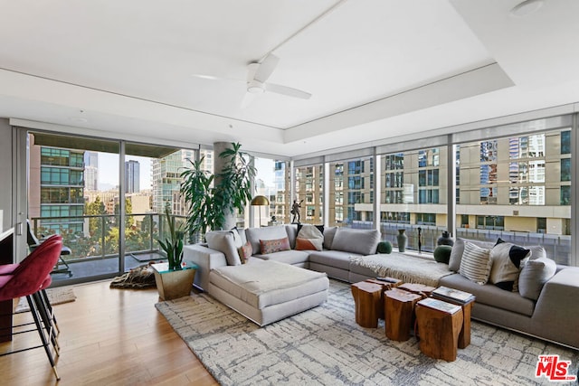 living room featuring light hardwood / wood-style flooring, a raised ceiling, and plenty of natural light