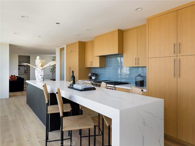 3100 Tennyson Pl, Hermosa Beach, CA 90254 - kitchen with light wood finished floors, decorative backsplash, a spacious island, light stone counters, and a breakfast bar area
